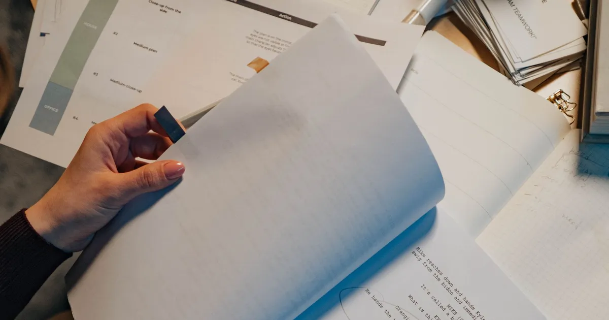 A person reviewing study notes and an open notebook at a desk