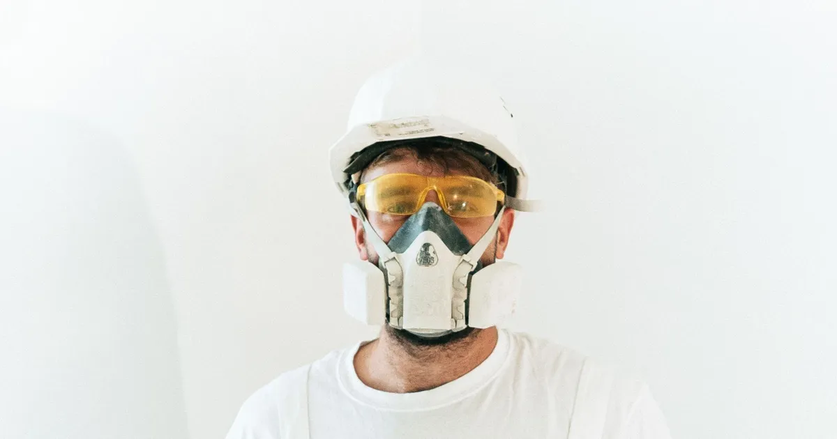 Contractor in a hard hat, safety glasses, and a respirator mask for lead-safe renovation work