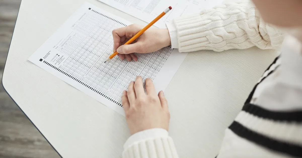 A person filling in a multiple-choice exam answer sheet with a pencil